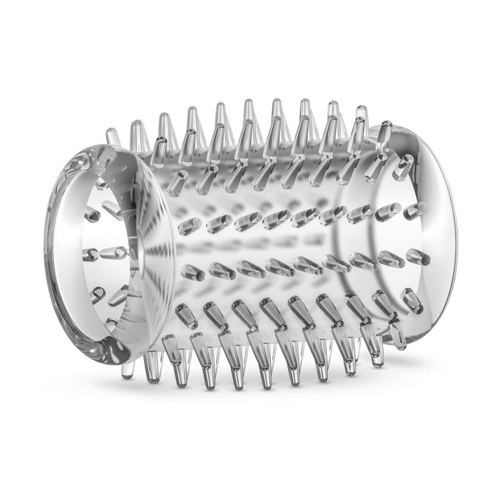 A Stay Hard Cock Sleeve with Texture Nubs by Blush, with conical spikes protruding from its surface, likely an attachment for a kitchen appliance like a food processor or grater. The drum has an open end and a closed end with a mounting mechanism. Resembling the texture of a cock sleeve, the spikes are arranged in a uniform pattern.