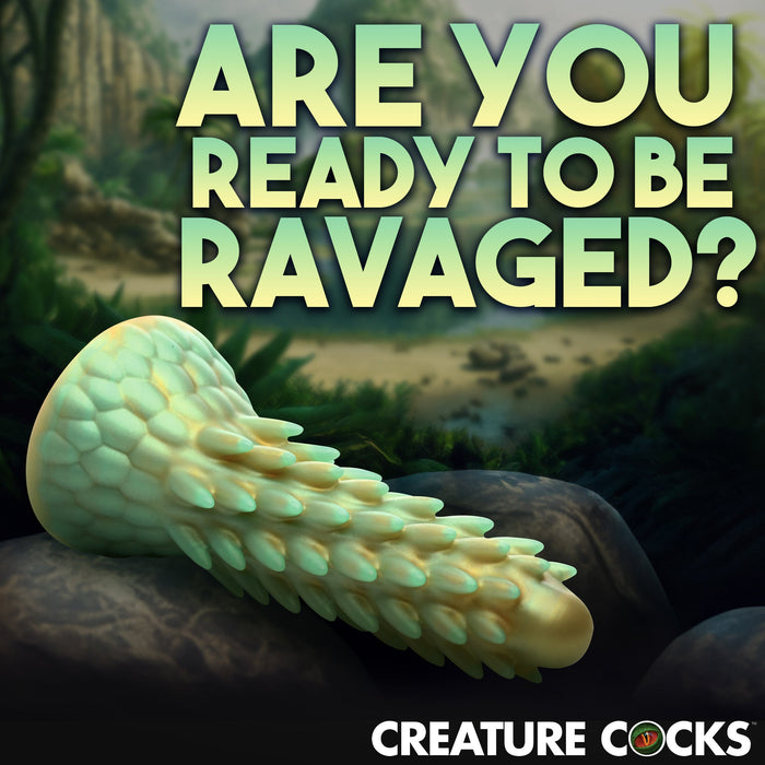 Image of a fantasy-themed, textured silicone sex toy placed on a rocky surface with a lush jungle in the background. Text reads, "ARE YOU READY TO BE RAVAGED?" Below, the logo and name "Stegosaurus Spiky Reptile Silicone Dildo by XR Brands" are displayed.