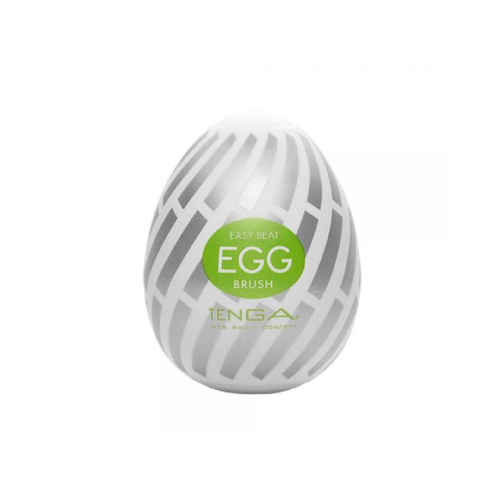 A white, oval-shaped Tenga Egg Disposable Penis Masturbator - Brush with a green label. The egg, perfect as a travel buddy, has a pattern of grey lines. The label reads "TENGA EGG DISPOSABLE PENIS MASTURBATOR - BRUSH" and "TENGA" in smaller letters, with additional text beneath. This Tenga Egg is your ideal disposable masturbation sleeve on the go.