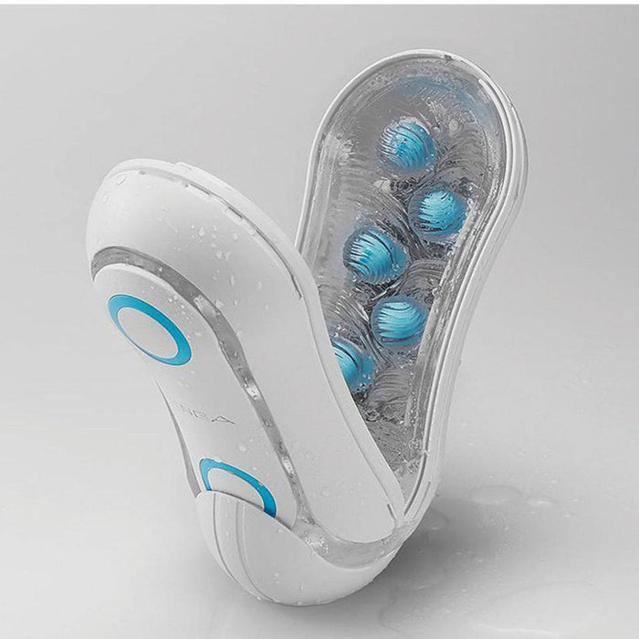 The image features a white Tenga Flip Orb Penis Masturbator - Blue Rush, characterized by its blue accents and multiple rotating blue pleasure orbs. The device appears slightly wet, suggesting it is water-resistant or waterproof. This Tenga product, resembling a handheld massager, is displayed against a neutral background.