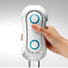 A hand is holding a sleek, white Tenga Flip Orb Penis Masturbator - Blue Rush device, featuring two blue circular buttons on its front. The curved, futuristic design includes a clear compartment at the bottom and an adjustable pad for comfort. The brand name "Tenga" is prominently displayed in the center.