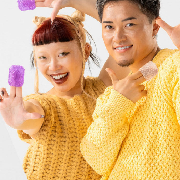 Two cheerful people in yellow sweaters displaying Tenga Uni Variety Pack Textured Finger Sleeves for Stroking and Clit Massage, making playful poses against a white background.