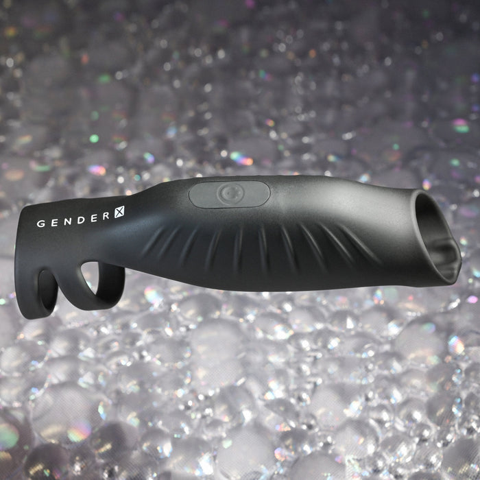 A black, elongated device with grooves and a circular button, labeled "The Rocketeer Vibrating Penis Enhancer Sheath - Black" by Evolved Novelties, is crafted from body-safe silicone and displayed against a background of shimmering bubbles.