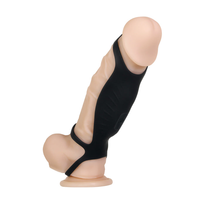 The Rocketeer Vibrating Penis Enhancer Sheath - Black by Evolved Novelties stands upright, featuring a flesh-toned, realistic silicone design with a suction base. It is partially covered with a black harness-like strap around its shaft. Made from body-safe silicone, it showcases a smooth head, veined texture, and a pronounced curve.