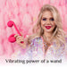 A blonde woman holds The Snail Ultra Powerful 2 Motor Dual Stimulating Vibrator in pink against a pink feathered background. She is smiling and wearing vibrant makeup with glittery, iridescent clothing. The text at the bottom reads, "Vibrating power of a wand," by Snail Vibe.