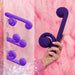 A hand holds "The Snail Ultra Powerful 2 Motor Dual Stimulating Vibrator - Purple" from Snail Vibe against a pink background. To the left, three instructional diagrams illustrate different ways to insert a pin into the device, emphasizing connection points and functionality, while highlighting its waterproof silicone construction.