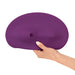 A hand holding the Orion VibePad 2 Ride On Hands-Free Humping Vibrator with Licking Tongue, which is purple, round, and flexible with a slight depression and a small cylindrical indentation. The background is plain white; this waterproof accessory boasts subtle elegance and practicality.