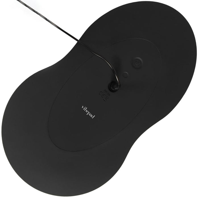 An overhead view of a black, bean-shaped device with a cord attached at the top. The device has smooth, rounded edges and the word "Orion" is visible in white on the surface. This sleek accessory is known as the VibePad 3 Ride On Hands-Free Humping Vibrator with G-Spot Probe and acts as a wireless remote control for added convenience.