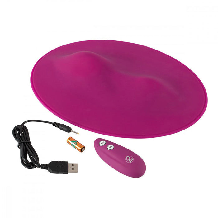 The Orion VibePad Ride On Hands-Free Humping Vibrator is a pink, oval-shaped electronic device featuring two raised bumps. It comes with a matching waterproof remote control that has two buttons for hands-free external stimulation, a USB charging cable, and a battery.