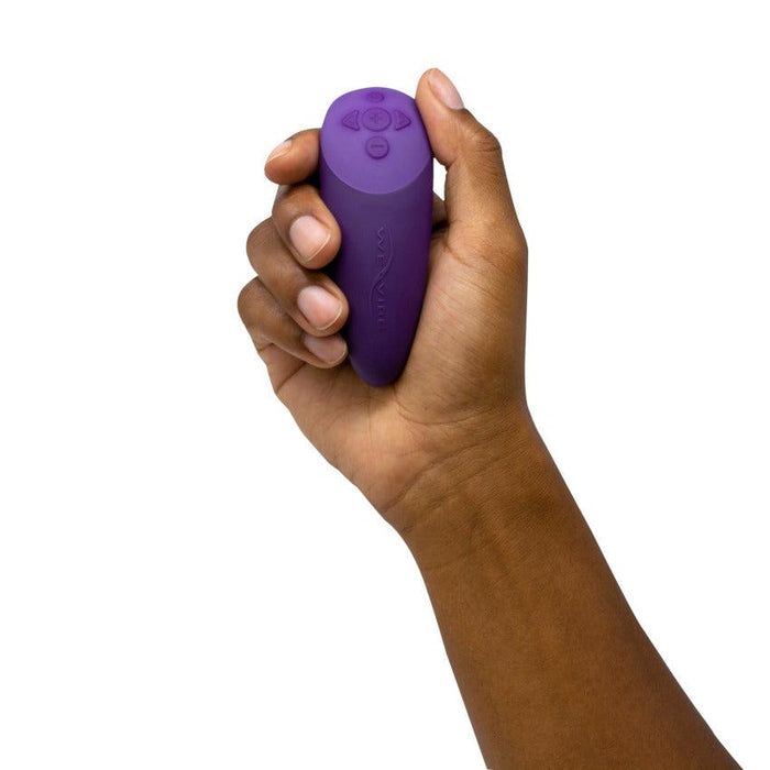 A person is holding a small, purple handheld device with control buttons on the top. Highlighting its compact size and ergonomic shape, the We-Vibe Chorus Remote & App Controlled Couples' Vibrator - Purple by We-Vibe also features touch-sensitive vibrations for an enhanced experience.