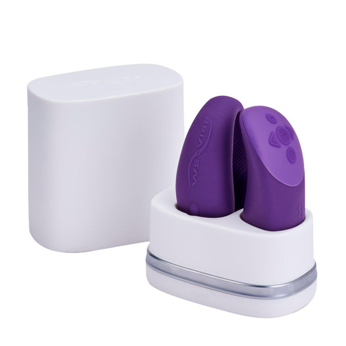 Image of the We-Vibe Chorus Remote & App Controlled Couples' Vibrator in purple, featuring touch-sensitive vibrations and an adjustable fit, placed in a white charging case. The device, from the renowned brand We-Vibe and designed for intimate use, showcases ridged and smooth textures. The lid of the white charging case is shown in the background.