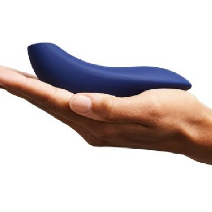 A hand is holding a sleek, blue, curved object, the We-Vibe Melt Rechargeable Pleasure Air Clitoral Stimulator by We-Vibe, against a plain white background.