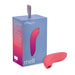 A box showcasing the "We-Vibe Melt Rechargeable Pleasure Air Clitoral Stimulator - Coral" and its clitoral air pulse stimulation technology is displayed. The box is primarily blue with a gradient of red and pink near the bottom. It features an image of a curved, coral-colored item, depicted alongside on the box and known for delivering intense pulsations. The top of the packaging includes a gray handle.