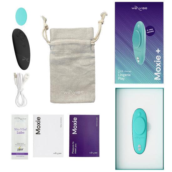 The We-Vibe Moxie+ Hands-Free Remote or App Controlled Panty Vibrator in teal, along with a black remote, USB charging cable, storage pouch, instruction manuals, and sachets of We-Vibe Lube are displayed against a white background. The product packaging is also visible.