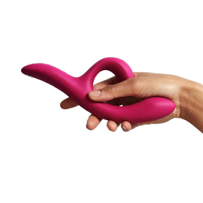 A person holding a pink We-Vibe Nova 2 Powerful Flexible G-Spot Rabbit Vibrator with an ergonomically designed looped handle and two curved ends against a white background.