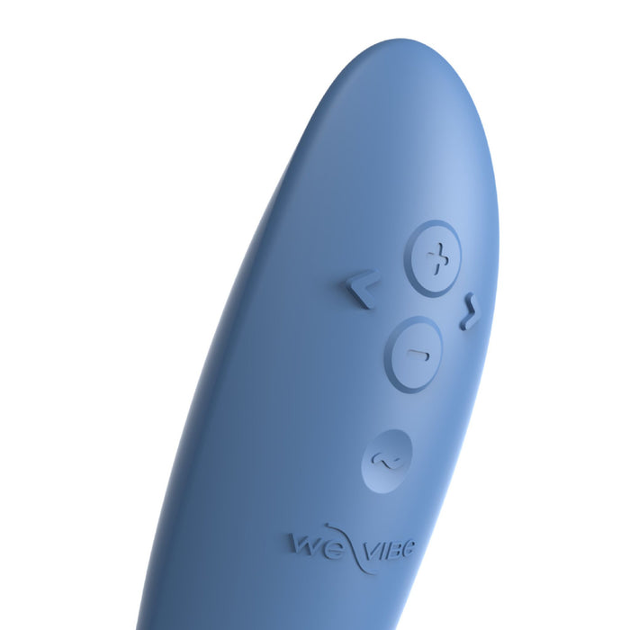 A close-up image of the We-Vibe Rave 2 Powerful Adjustable G-Spot Vibrator in blue, showcasing its curved design and control buttons. There are four raised buttons in total: a plus (+), a minus (-), a power button, and a wavy icon, with an embossed We-Vibe logo beneath the buttons.