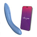 A blue We-Vibe Rave 2 Powerful Adjustable G-Spot Vibrator is shown next to a smartphone with a purple and pink gradient screen displaying the We-Vibe logo. The vibrator has buttons on its surface, and the smartphone appears to be part of an app to control the device.