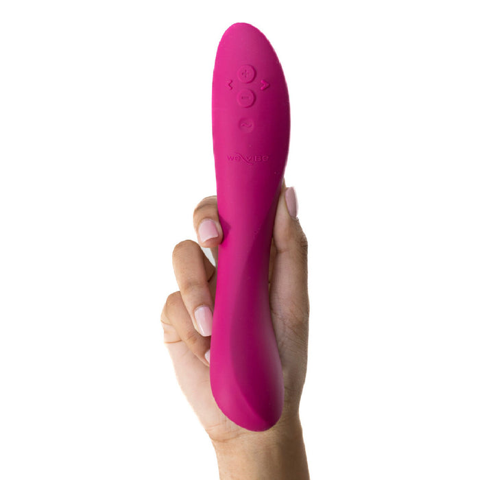 A hand holding a slender, curved fuchsia G-spot vibrator with control buttons on its surface. The We-Vibe Rave 2 Powerful Adjustable G-Spot Vibrator has a smooth texture, is ergonomically designed for comfortable use, and is app-enabled.