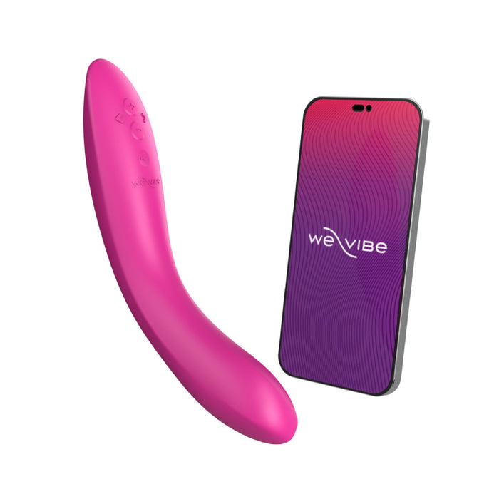 A fuchsia We-Vibe Rave 2 Powerful Adjustable G-Spot Vibrator with control buttons on its side is pictured next to a smartphone displaying a purple and pink gradient screen with the "We-Vibe" logo. The massager and phone, part of the We-Vibe Rave 2 set, appear to be app-enabled for seamless connectivity.