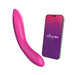 A fuchsia We-Vibe Rave 2 Powerful Adjustable G-Spot Vibrator with control buttons on its side is pictured next to a smartphone displaying a purple and pink gradient screen with the "We-Vibe" logo. The massager and phone, part of the We-Vibe Rave 2 set, appear to be app-enabled for seamless connectivity.