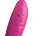 Image of a fuchsia, handheld electronic device with buttons. The We-Vibe Rave 2 Powerful Adjustable G-Spot Vibrator - Fuchsia from We-Vibe features a plus button, left and right arrow buttons, a circular button, and a squiggly line button. The app-enabled G-spot vibrator has the word "We-Vibe" printed on it.