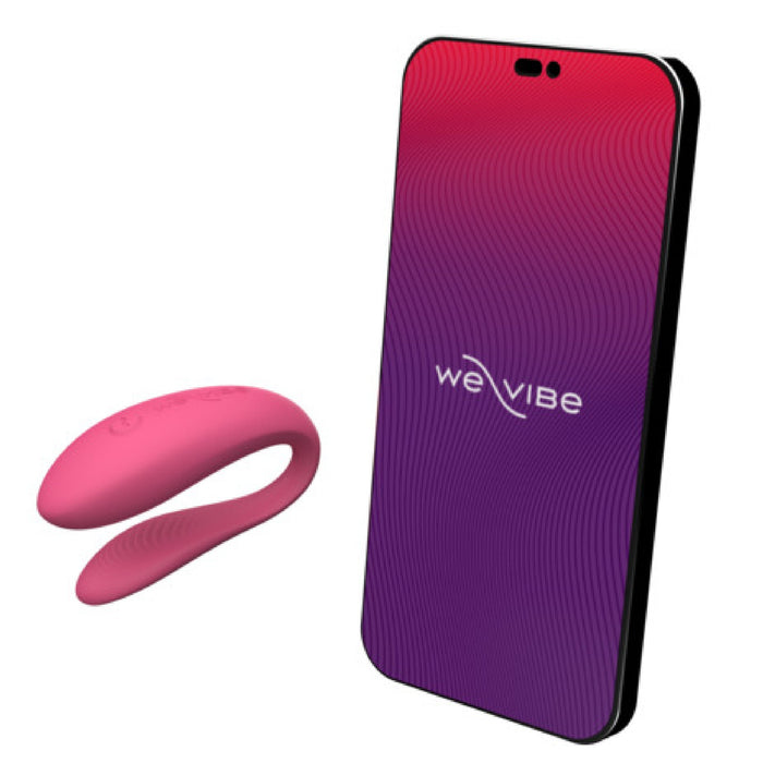 Image of a pink We-Vibe Sync Lite App Controlled Wearable Couples Vibrator next to a smartphone displaying the We-Vibe logo on its screen. The intimate-use device is shown against a gradient red-to-purple background with wavy lines on the phone's display.