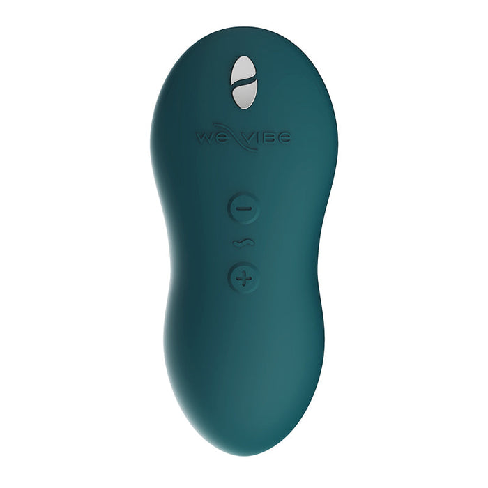 The We-Vibe Touch X Lay On Vibrator in green features an oval-shaped, silicone-coated wireless remote control adorned with the brand name "We-Vibe." The remote is designed for effortless use, boasting three buttons: a plus sign (+) at the bottom, a wavy line in the center, and a minus sign (-) at the top.