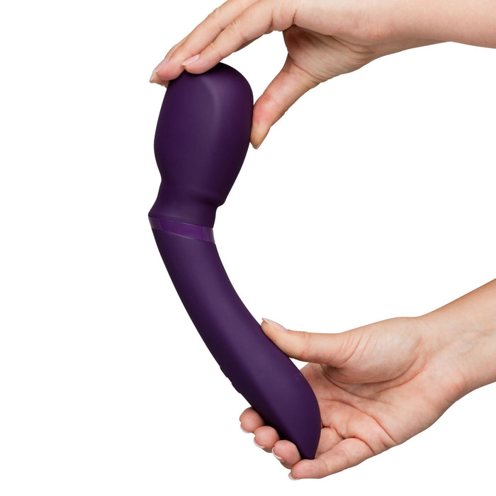 Two hands display the We-Vibe Wand 2 by bending its purple, flexible structure. This powerful cordless waterproof vibrator features an ergonomic design with a broader end and a tapered handle.