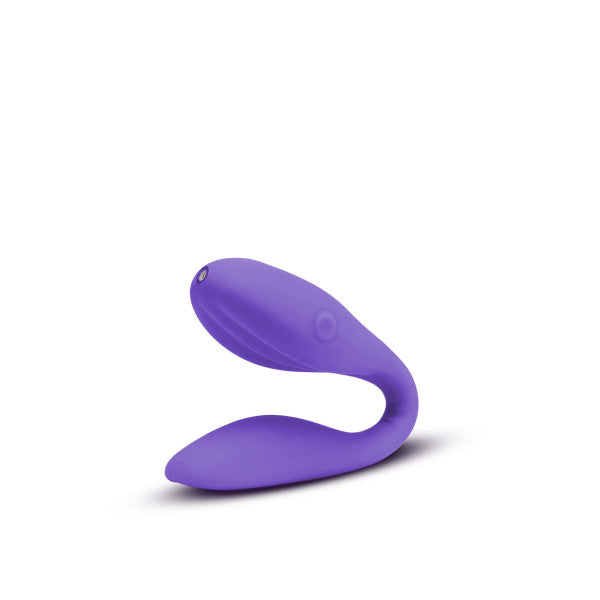 A purple, U-shaped wearable vibrator named the Wellness Duo Hands Free Wearable and Couples Vibrator by Blush, made from Puria™ silicone, isolated on a white background. The device features smooth, curved ends and a minimalist design with versatile vibration functions.