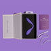 An open box displays the Blush Wellness Duo Hands Free Wearable and Couples Vibrator with a curved design made of Puria™ silicone against black padding, alongside a purple wellness guide, a white charging cable, and the box lid inscribed with "Made for your moves." The background is a matching shade of purple.