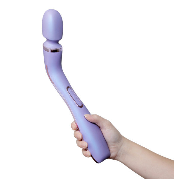 A hand is holding the Wellness Eternal Slim Ergonomic Powerful Remote Control Wand by Blush in a beautiful lavender color. The wand-style personal massager features an elongated handle and a rounded head. It is waterproof and has a couple of visible buttons on the side, likely for controlling its powerful vibrations.