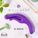 A Wellness G Wave Waterproof Rabbit Vibrator with Ergonomic Handle in purple is showcased against a white surface, accompanied by a green leafy plant, face roller, and golden lipstick case. The words "WELLNESS" and "G WAVE" appear above the vibrator. Designed for pleasure with its ergonomic clit and g-spot hugging shape, the Blush logo graces the bottom left corner.