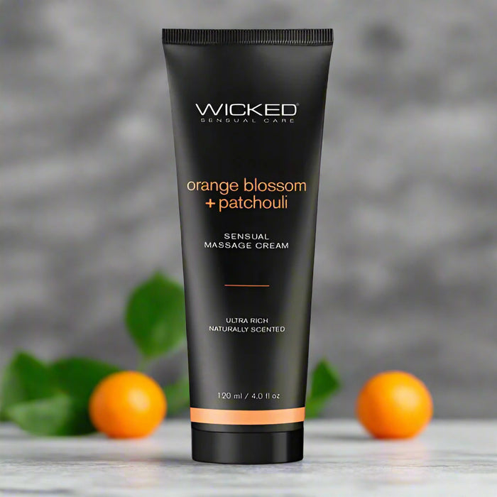 A 120 ml tube of Wicked Sensual Orange Blossom & Patchouli Massage Cream from the brand "Wicked Lubes." The label reads "orange blossom + patchouli" and "sensual massage cream, ultra rich, naturally scented." The sleek black tube features vibrant orange and white text.