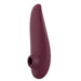 A bordeaux, ergonomically designed personal massager with a sleek, curved shape and a circular opening at the base. Featuring innovative Pleasure Air pulsation for enhanced clitoral stimulation, the Womanizer Classic 2 Pleasure Air Clitoral Stimulator by Womanizer appears seamless and compact, suggesting portability and easy handling.