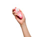 A person's hand holding the Womanizer Liberty 2 Pleasure Air Travel Sized Clitoral Stimulator - Rose against a white background. This compact, waterproof sex toy by Womanizer features a round head and control buttons, perfect for personalized use.