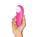 A person holding a pink Womanizer Starlet 3 Pleasure Air Clitoral Stimulator from the brand Womanizer, featuring a white circular attachment at one end, against a white background.