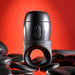 A Wet It Be Hand Held Vibrating Masturbator with Lube Dispenser by Evolved Novelties is positioned upright against a vivid red background. The waterproof sex toy is surrounded by smooth black stones, creating a contrast with the bright backdrop and emphasizing its sleek design.