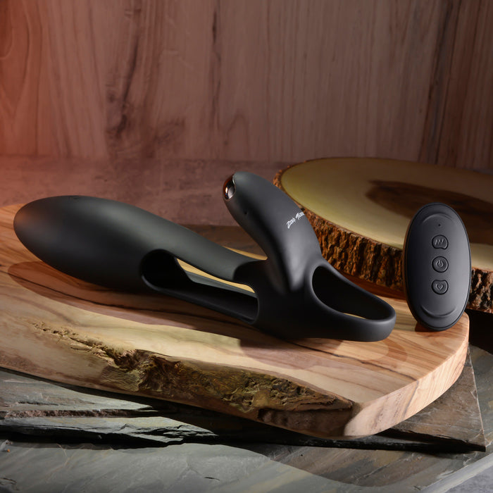 The Nautilus Rechargeable Vibrating Penis Sleeve for Couples, with its ergonomic design and three-button remote control, is displayed on a wooden surface. A rustic wood slice and stone-like background enhance its sophisticated appeal.