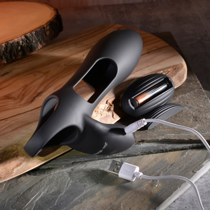 A sleek, modern black Nautilus Rechargeable Vibrating Penis Sleeve with USB charging cable rests on a wooden surface. This versatile couples' vibrator features smooth curves, openings, and a textured attachment for shared relaxation and intimate moments.