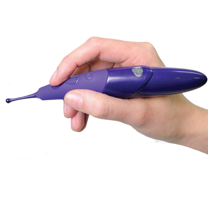 A hand holding a sleek, purple Zumio X Powerful Oscillating Rechargeable Clitoral Stimulator with a thin, pointed tip featuring Spiro Tip Technology and a small control button. The tool appears modern and ergonomically designed. The background is plain white.