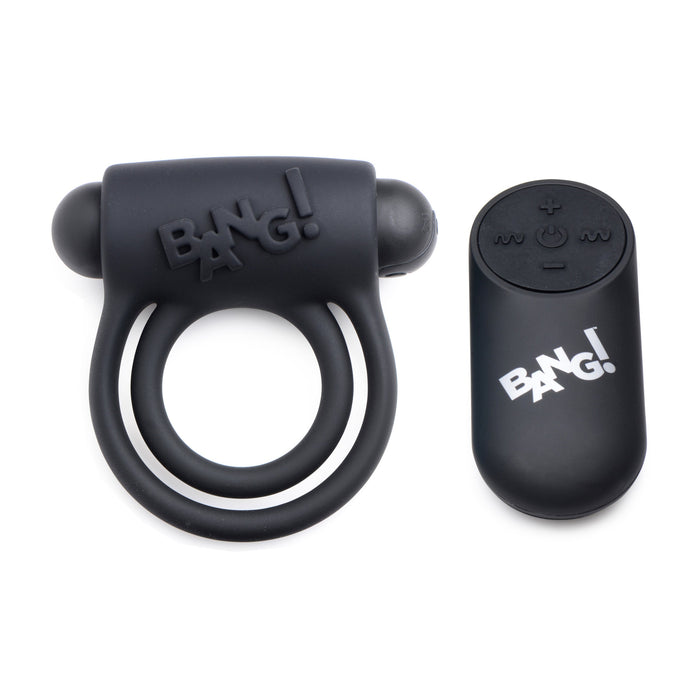 A black silicone sex toy, known as the Bang! Cock Ring with Vibrating Bullet and Remote Control by XR Brands, featuring two loops and a control pad adorned with the "BANG!" logo. The control pad includes buttons for power, intensity, and mode adjustment.