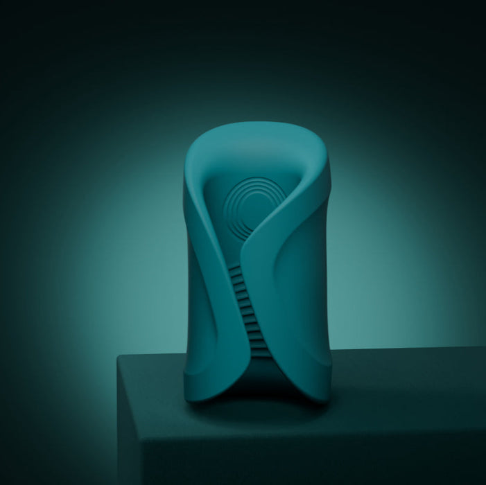 A sleek teal Lovense Gush 2 oscillating masturbator with smooth curves and a circular pattern stands on a dark surface against a gradient teal background, offering modern design and app compatibility for a hands-free experience.