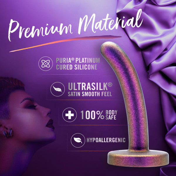 The image displays Blush's Surrender Slim 4.75 Inch Silicone Beginner & Pegging Dildo in a luxurious purple and gold color scheme, featuring a sleek, curved design perfect for pegging enthusiasts. It highlights the "Puria Platinum Cured Silicone," "Ultrasilk Satin Smooth Feel," "100% Body Safe," and "Hypoallergenic" features against a rich purple backdrop adorned with silky fabric.