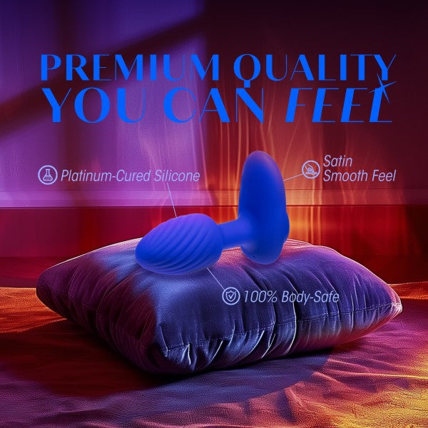 A Blush Mystery Vibrating Textured Silicone Butt Plug in Sapphire rests on a satin pillow under colored lighting. Text reads "Premium Quality You Can Feel" and highlights features: "Platinum-Cured Silicone," "Satin Smooth Feel," and "100% Body-Safe.