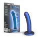 Image of a Blush Surrender Intermediate 5.75 Inch Silicone Beginner & Pegging Dildo, showcasing a blue-purple gradient silicone shaft designed for effortless pegging. The dildo is artfully positioned beside its packaging, which displays product details and features.